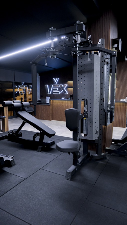 VEX Athletic Club salonu; ağırlık istasyonları ve arka planda karşılama bankosu